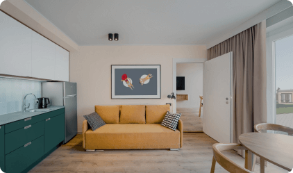 Living room with sofa and kitchennete within the Bungalow located in the official accommodation facility of Park of Poland, Suntago Village