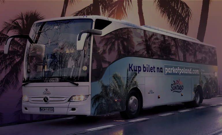 Suntago bus decorated with palm tree graphics. The side of the bus displays the text "Buy a ticket at parkofpoland.com". In the background, silhouettes of palm trees against the setting sun.