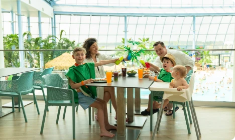 Family with children having a meal in a restaurant overlooking the pool