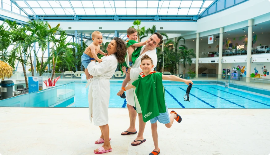 Family by the pool, parents with children in robes and towels, ready for fun at Suntago