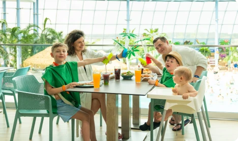 Family with children having a meal in a restaurant overlooking the pool