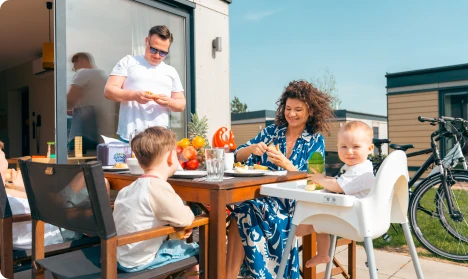 Family enjoying a meal outdoors in front of a bungalow at Suntago Village