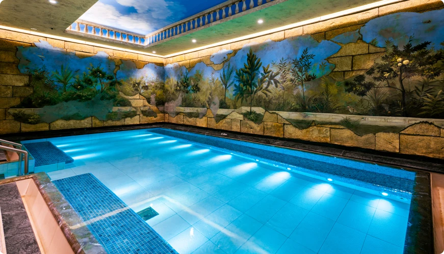 Warm indoor pool with tropical murals on the walls