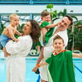 Family by the pool, parents with children in robes and towels, ready for fun at Suntago