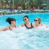 Three women relaxing in the Relax zone pool, tropical plants in the background