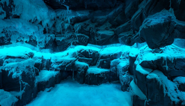 Jaskinia wypełniona lodowymi ścianami i zaśnieżoną podłogą, tworząca mroźną i czarującą scenę